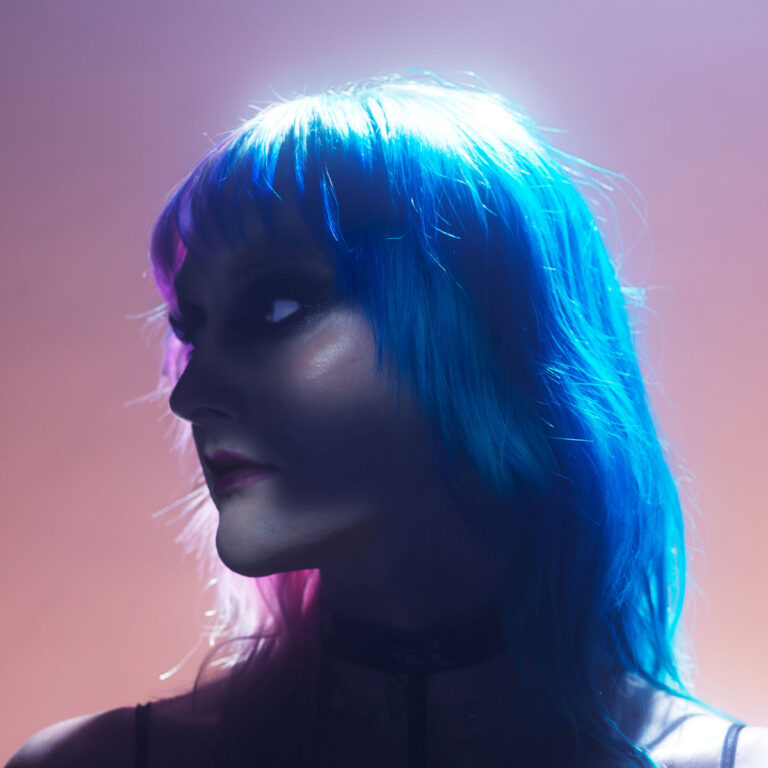 Porträt einer Person mit blau-pinkem Haar im dramatischen Gegenlicht vor violettem Farbverlauf – das Cover zu „You Are The Morning“ strahlt Stärke und Verletzlichkeit zugleich aus.
