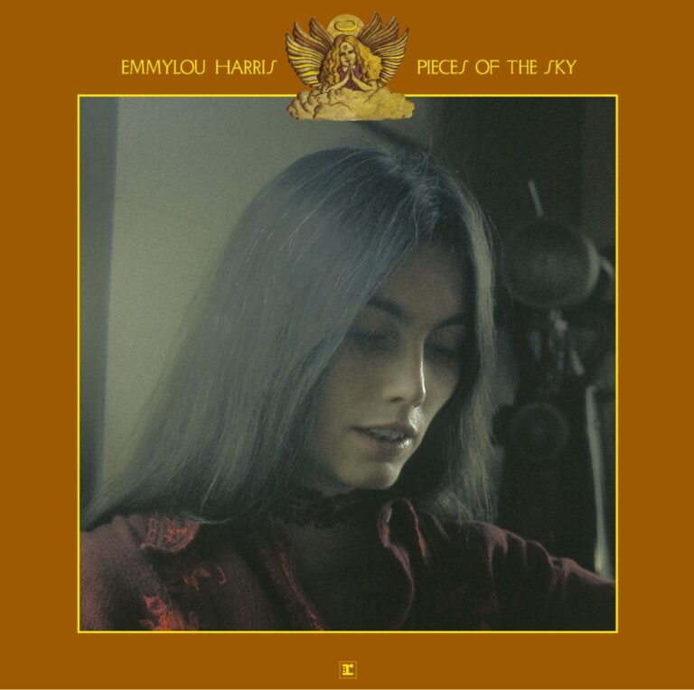 Emmylou Harris mit langen Haaren und rotem Oberteil, Blick nach unten, in einem Studio.