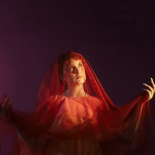 Phoebe Green in rotem Schleier und fließendem Kleid vor violettem Hintergrund – Cover der introspektiven Single What Are You Doing.