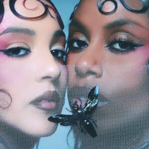 Porträt der Nova Twins mit aufwendigem Make-up und Netzschleier, durch den ein schwarzer Schmetterling fliegt – sinnlich, düster und symbolisch für Transformation und innere Schatten.