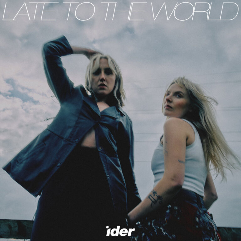 Zwei Frauen blicken in dramatischem Winkel in die Kamera unter wolkenverhangenem Himmel – Artwork zum introspektiven IDER-Album „Late to the World“.