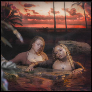 Das Cover zeigt Mahalia und Lila Iké in warmem Licht in einer tropischen Wasserlandschaft bei Sonnenuntergang – ein visuell poetisches Symbol für emotionale Tiefe und Selbstbehauptung.