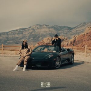 Kamaiyah sitzt im Gucci-Jogginganzug auf einem schwarzen Sportwagen, daneben ein Mann; Wüstenlandschaft und Berge im Hintergrund, Parental-Advisory-Label sichtbar.