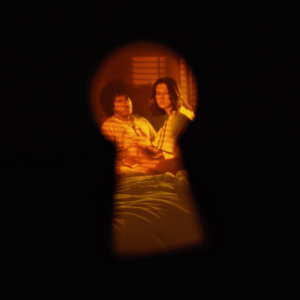 Durch ein Schlüsselloch fotografierte Szene: Selena Gomez und Gracie Abrams auf einem Bett in warmer Lichtstimmung – intimes Artwork zur gemeinsamen Single.