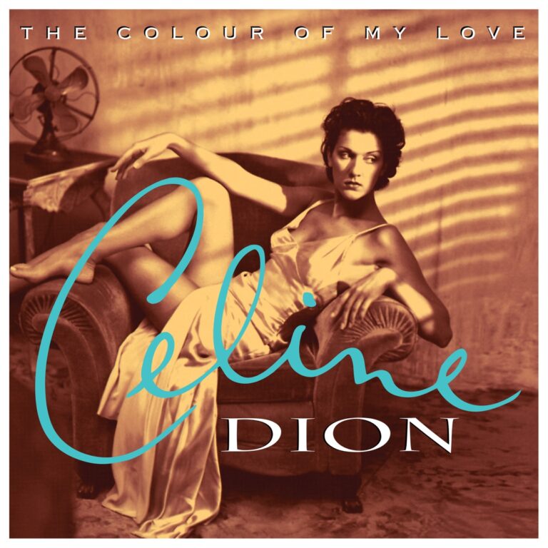 Céline Dion sitzt in einem eleganten Kleid auf einem Sessel, umgeben von warmem Licht.