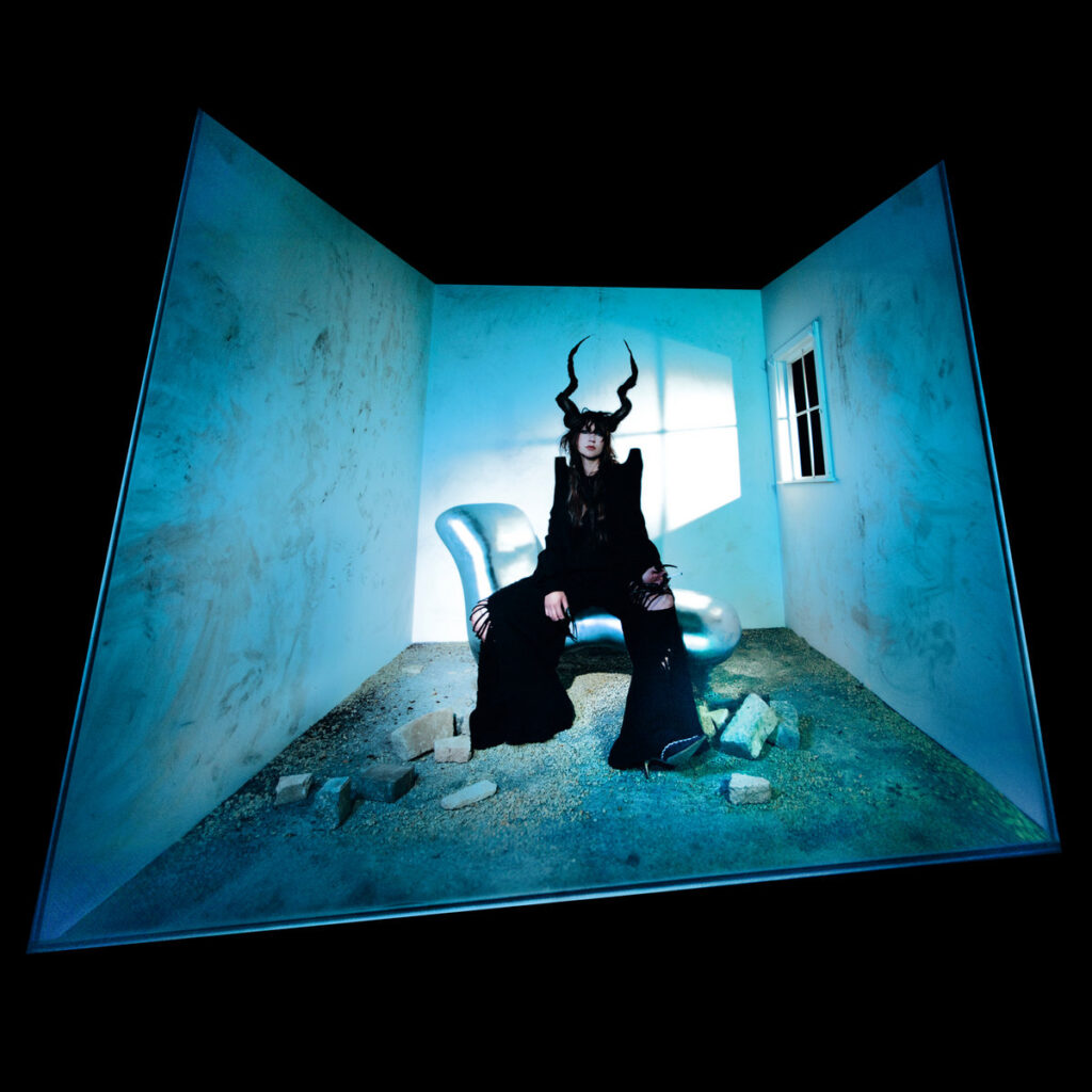 Albumcover von „Halo on the Inside“: Haley Fohr sitzt in einem verzerrten, leeren Raum; ihre Haare geformt zu geschwungenen Hörnern – eine Figur zwischen Mensch und Mythos. 