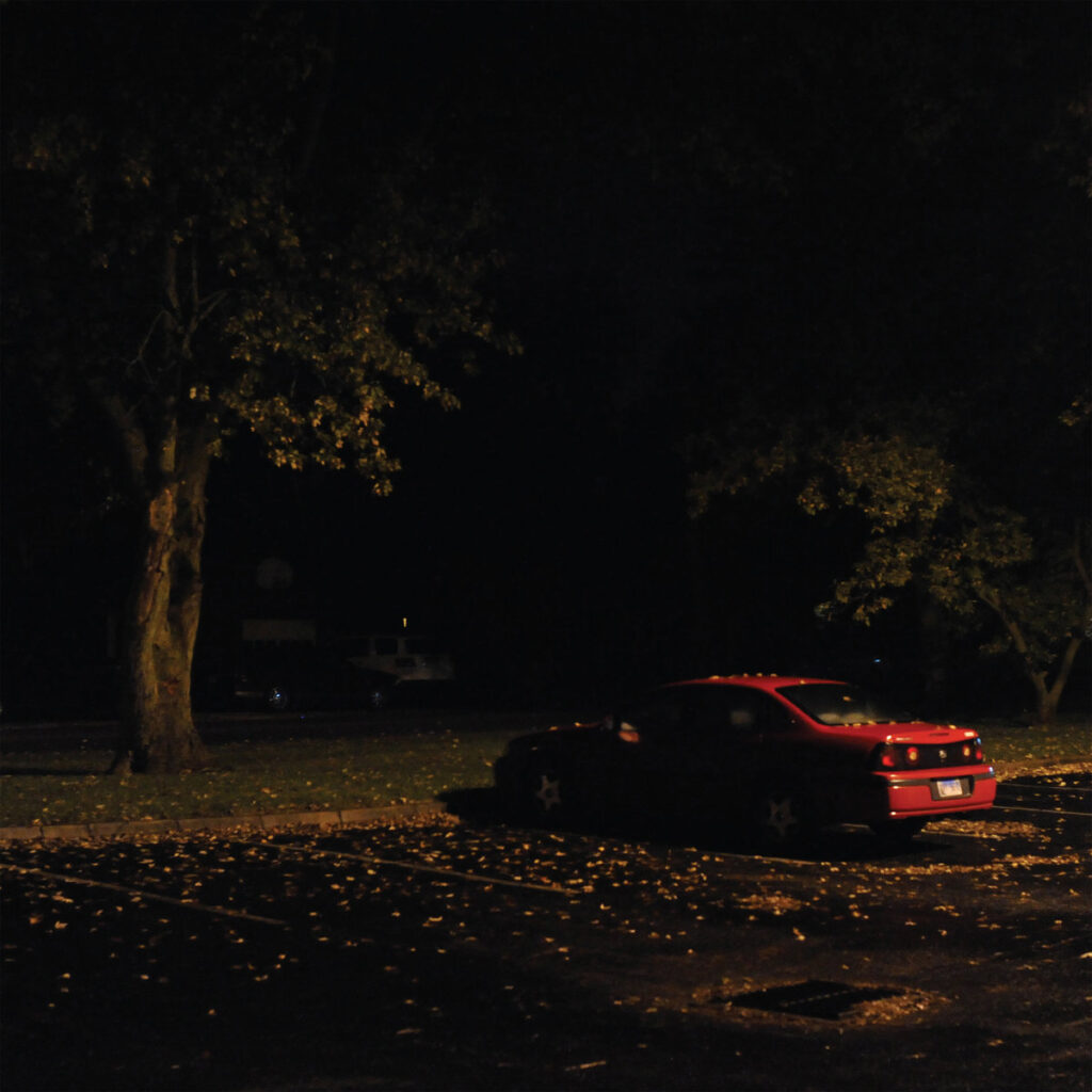 Albumcover von No Floor von More Eaze & Claire Rousay: Eine dunkle, nächtliche Szene mit einem roten Auto unter Bäumen, die eine ruhige Atmosphäre vermittelt.​
