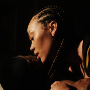Nahaufnahme von Madison McFerrin mit geflochtenem Haar, in inniger Pose mit einer weiteren Person – warmes Licht betont die emotionale Stimmung.