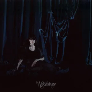Cover der Single „Unforgivable“ von Alexandra Savior: Die Künstlerin liegt nachdenklich auf einem dunklen Hintergrund mit Lichtpunkten, die eine verträumte Atmosphäre schaffen.​
