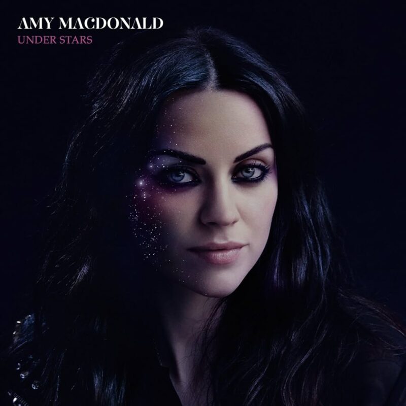 Cover des Albums Under Stars von Amy Macdonald: Die Sängerin vor dunklem Hintergrund mit Sterneneffekten über ihrem Gesicht, was die nachdenkliche, verträumte Stimmung des Albums visuell unterstreicht.