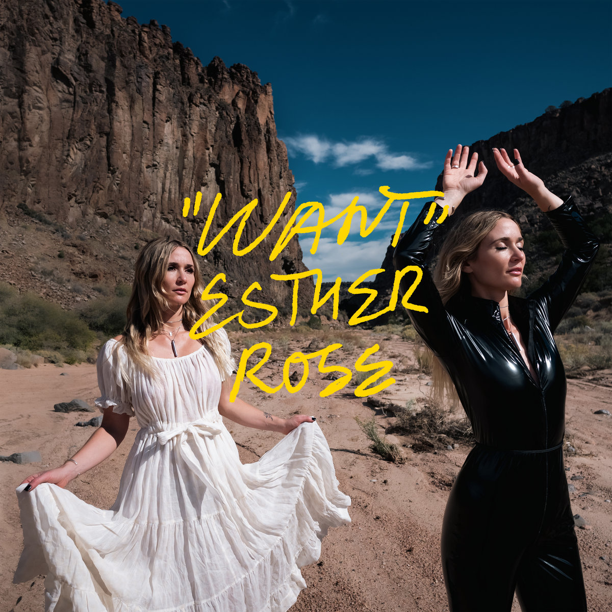 Zwei Frauen stehen in kontrastierenden Outfits – eine in weißem Kleid, die andere in schwarzem Latexanzug – in einer dramatischen Wüstenlandschaft vor einer Felswand. Die gelbe Handschrift “Want” Esther Rose ist darübergelegt.