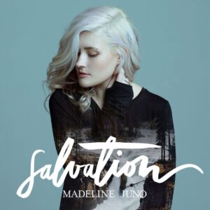 Madeline Juno mit hellblondem Haar vor bläulichem Hintergrund; ihr Pullover zeigt ein überlagertes Naturmotiv mit Fluss und Bäumen – Cover des Albums Salvation