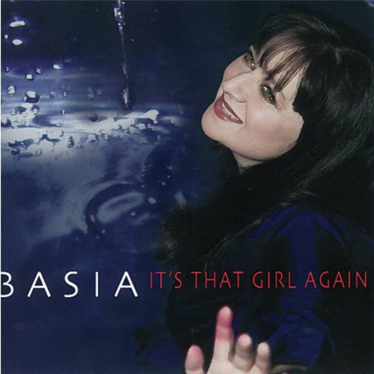 Basia blickt auf dem Albumcover zu „It’s That Girl Again“ strahlend zur Seite, vor einem wasserähnlichen blauen Hintergrund.
