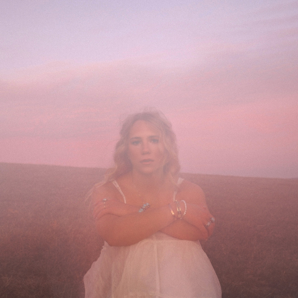 Avery Anna sitzt im rosa Nebel mit verschränkten Armen, allein auf weiter Flur – Cover von let go letters.