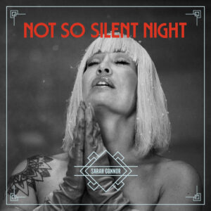 Albumcover von Sarah Connor Not So Silent Night mit betender Pose, weißblondem Bob und Art-Déco-Rahmen in Schwarz-Weiß