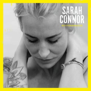 Schwarzweißporträt von Sarah Connor mit gesenktem Blick und Tattoo, eingerahmt von einem leuchtenden Gelb