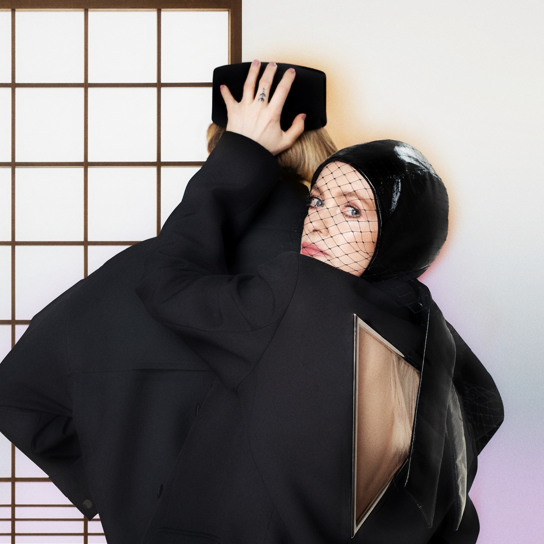 Zwei verschmolzene Figuren in futuristischen Outfits, Blick durch Netzschleier, inspiriert von Alison Goldfrapps „Reverberotic“-Artwork.