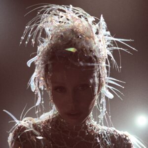 Miley Cyrus mit irisierendem Kristallkopfschmuck im Gegenlicht – Albumcover von „Something Beautiful“