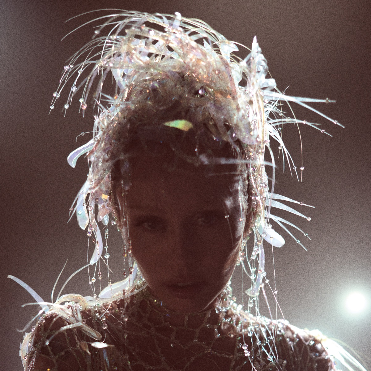 Miley Cyrus mit irisierendem Kristallkopfschmuck im Gegenlicht – Albumcover von „Something Beautiful“