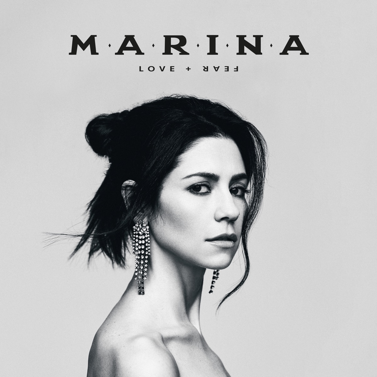 MARINA auf dem Cover von „LOVE + FEAR“ – in Schwarz-Weiß, mit ernstem Blick und schimmernden Ohrringen, radikal reduziert inszeniert.