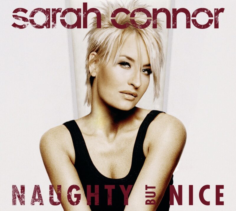 Sarah Connor auf dem Albumcover von „Naughty but Nice“ (2005) mit strengem Blick, Platinfrisur und zurückhaltender Eleganz