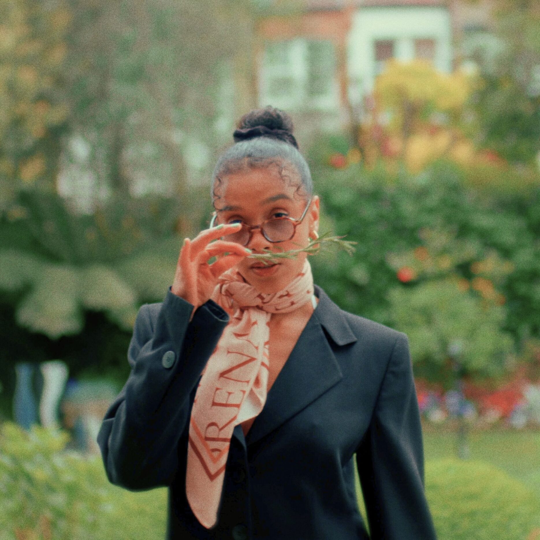 Ruby Francis mit Sonnenbrille und Halstuch vor verschwommenem Garten – geheimnisvoll und stilisiert wie das Cover zu „Lanzarote“.