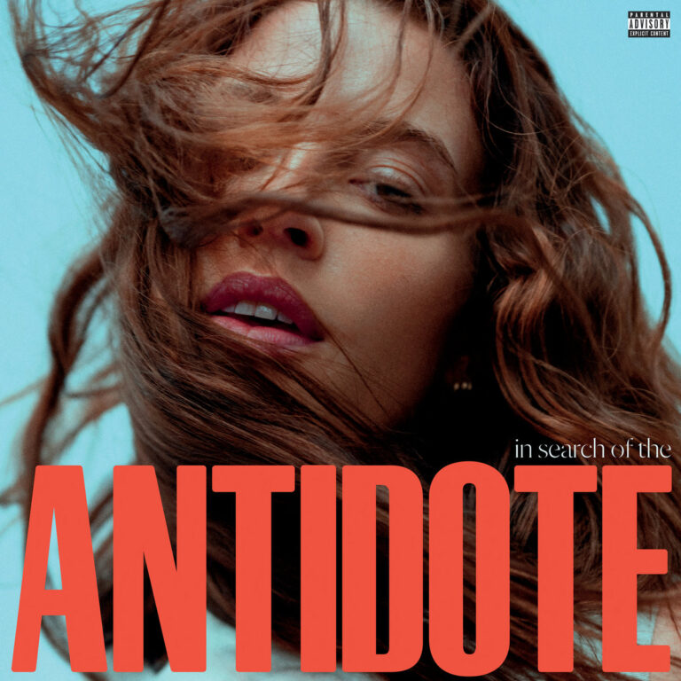 Albumcover von FLETCHERs „In Search Of The Antidote“ mit großem roten Titeltext und windverwehten Haaren über dem Gesicht der Künstlerin.