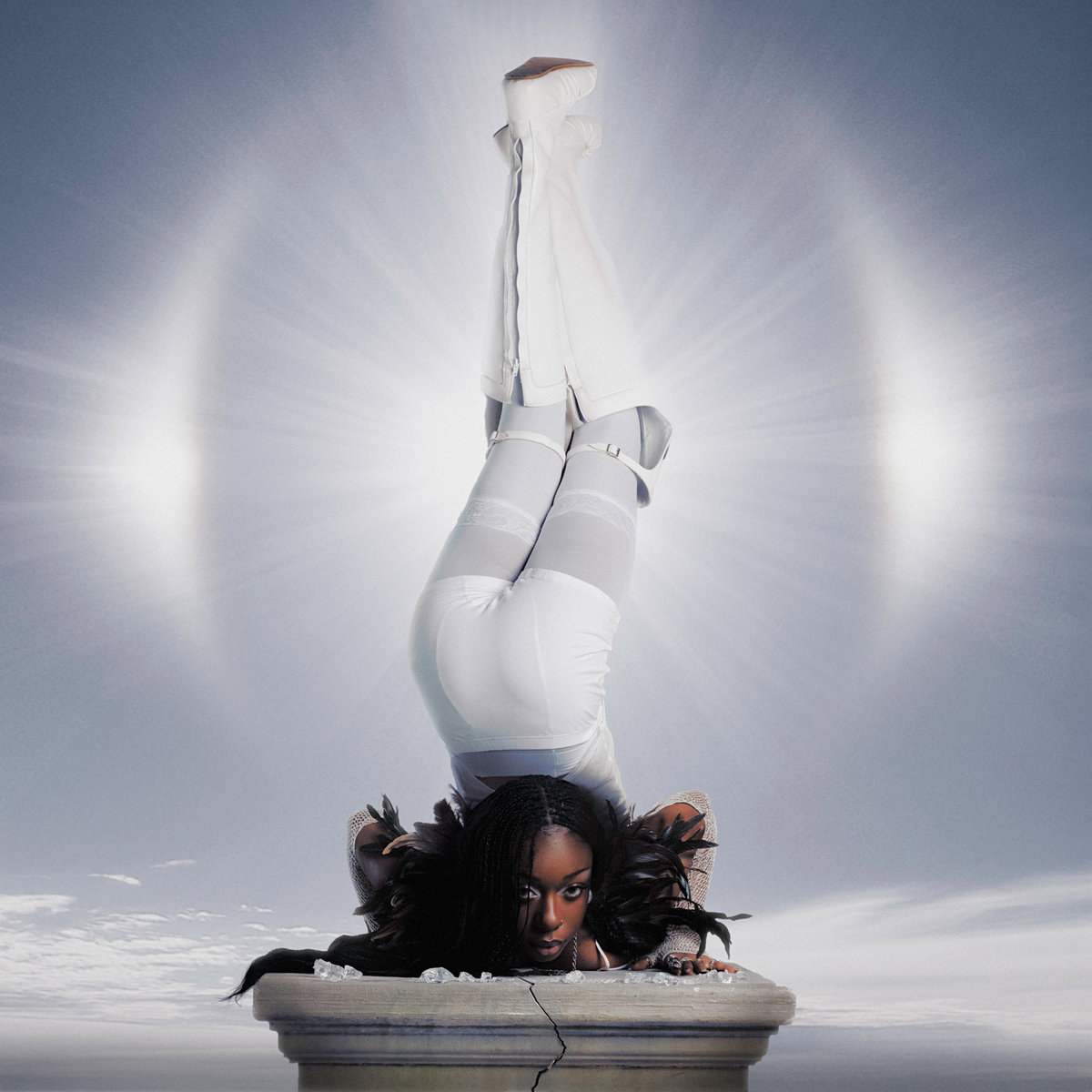 Debby Friday thront kopfüber, invertiert auf zerbrochener Säule vor strahlenförmigem Licht.
