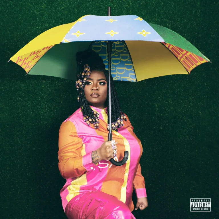 Kamaiyah mit buntem Regenschirm vor grünem Hintergrund, kraftvoll und selbstbewusst inszeniert.