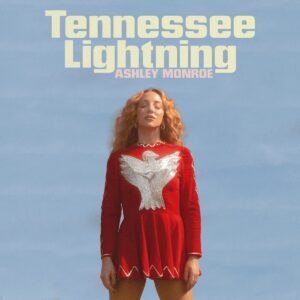 Ashley Monroe im roten Kleid mit silberner Taube vor blauem Himmel – Cover des Albums „Tennessee Lightning“