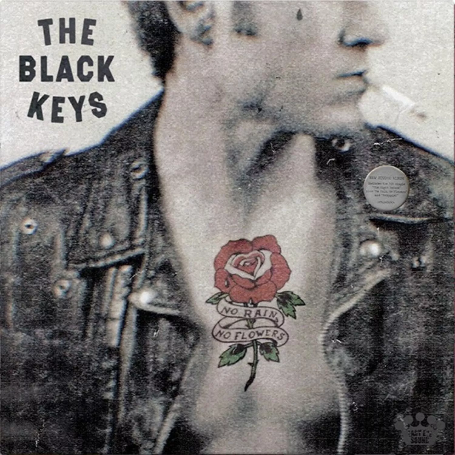 Verschwommenes Porträt eines Mannes in Lederjacke mit Rose-und-Banner-Tattoo „No Rain No Flowers“ auf der Brust, Albumcover von The Black Keys.
