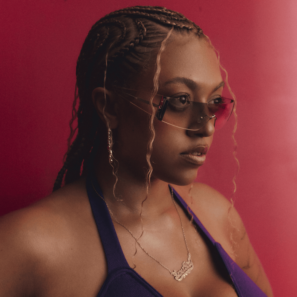 Porträt von Mahalia mit Sonnenbrille vor rotem Hintergrund, geflochtene Haare, ernster Blick, aus dem Luvergirl-EP-Cover