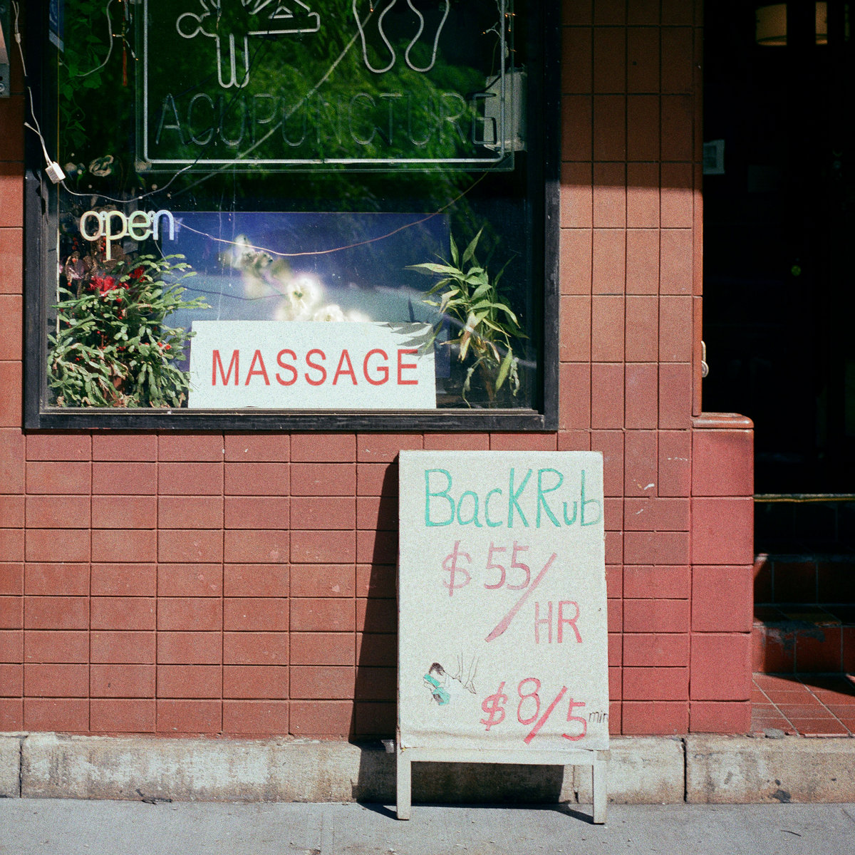 Albumcover zeigt ein Straßenschild vor einem Massage-Studio mit handgeschriebener Preisangabe.