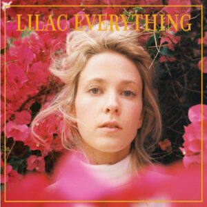 Albumcover von Lilac Everything zeigt Emma Louise vor leuchtend pinken Blüten, ihr Gesicht ernst und verletzlich im Vordergrund.
