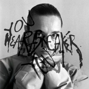 Schwarz-weißes Albumcover von Jehnny Beth „You Heartbreaker, You“ mit ernstem Porträt und darüber gekritzeltem Schriftzug.