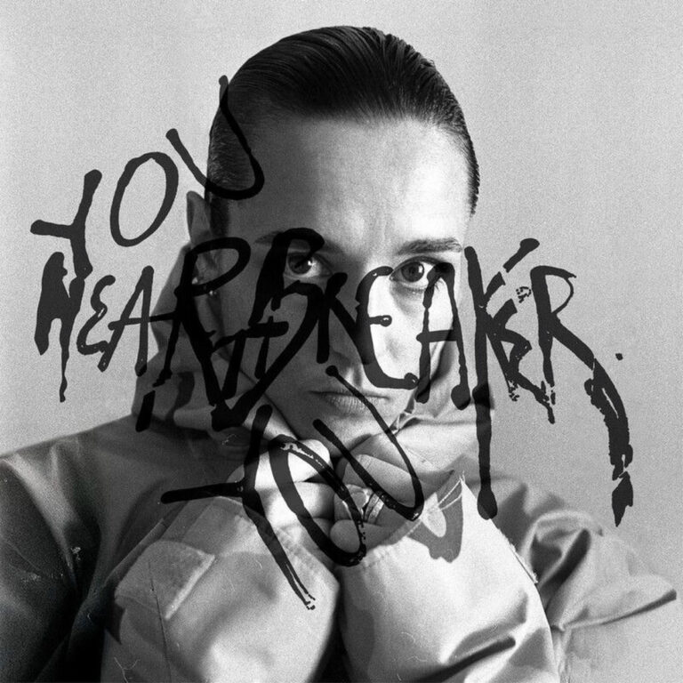 Schwarz-weißes Albumcover von Jehnny Beth „You Heartbreaker, You“ mit ernstem Porträt und darüber gekritzeltem Schriftzug.