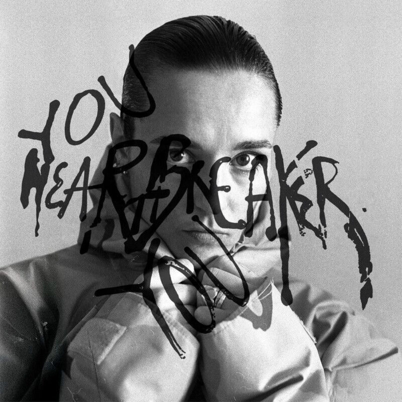 Schwarz-weißes Albumcover von Jehnny Beth „You Heartbreaker, You“ mit ernstem Porträt und darüber gekritzeltem Schriftzug.