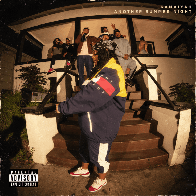 Albumcover von Kamaiyah – Another Summer Night, die Rapperin im bunten Windbreaker vor einer Veranda mit Crew im Hintergrund.