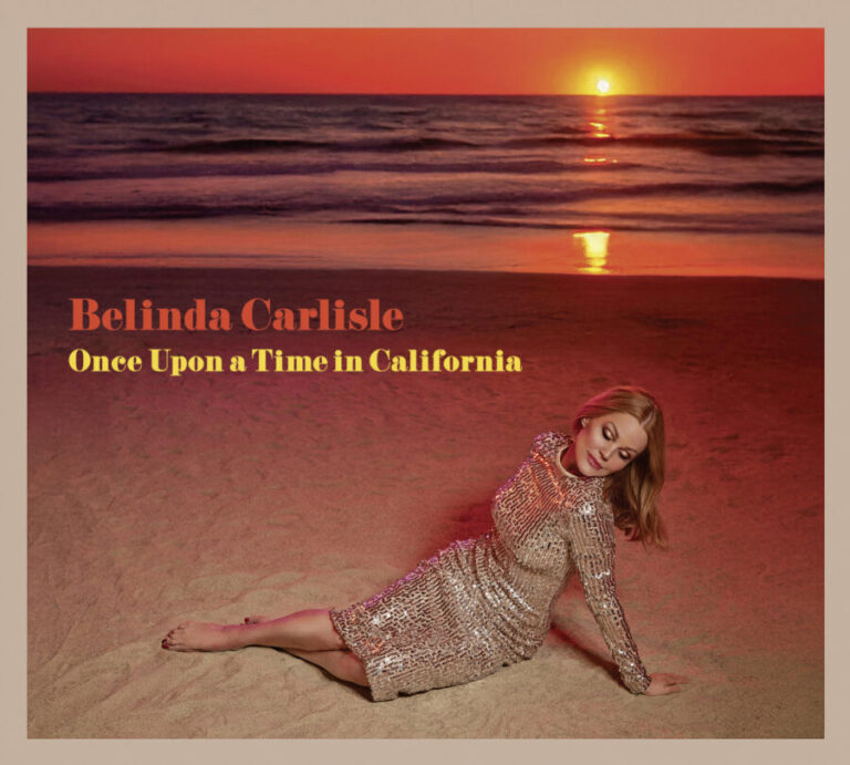 Belinda Carlisle sitzt im glitzernden Kleid in der Abendsonne auf einem Strand, hinter ihr der rot leuchtende Pazifik-Horizont, Albumtitel in warmem Orange.