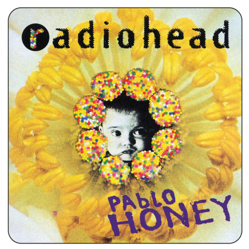 Gelbes Blütenmotiv in Nahaufnahme, mittig ein schwarz-weißes Babygesicht, umrahmt von bunten Zuckerkügelchen; oben der Schriftzug „radiohead“, unten der violette Titel „Pablo Honey“.