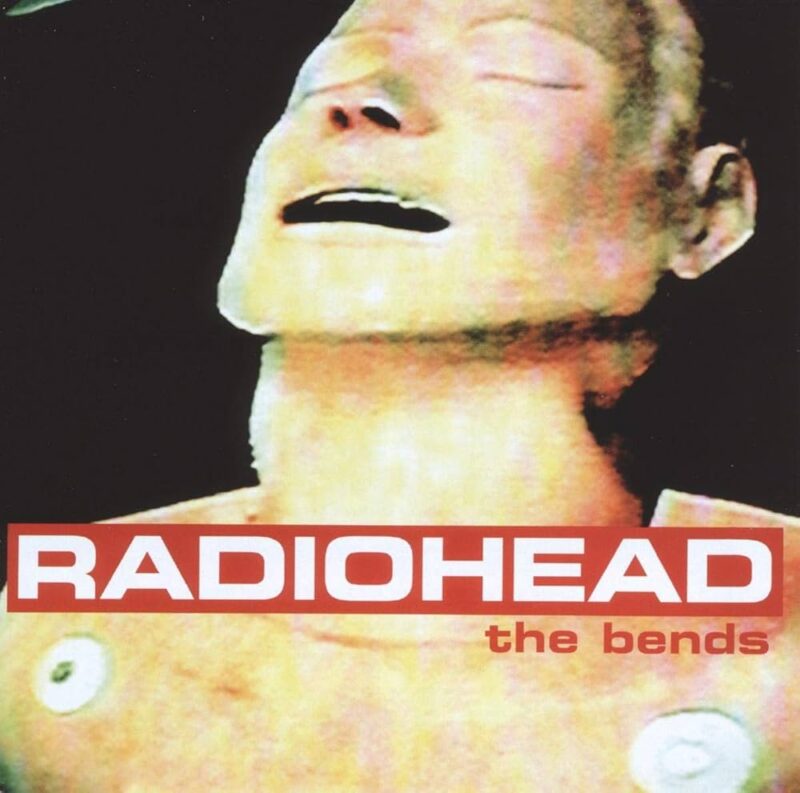 Grobkörniges Albumcover mit schwarzem Hintergrund: ein blass-beiger CPR-Dummy im Anschnitt, Augen geschlossen, darüber ein roter Balken mit weißer Schrift „RADIOHEAD“, kleiner gelb „the bends“.