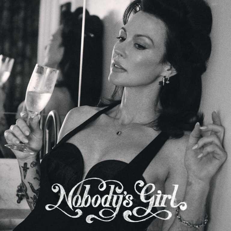 Schwarz-weißes Albumcover von Amanda Shires „Nobody’s Girl“, die in eleganter Pose mit Champagnerglas und ernstem Blick nachdenklich wirkt.