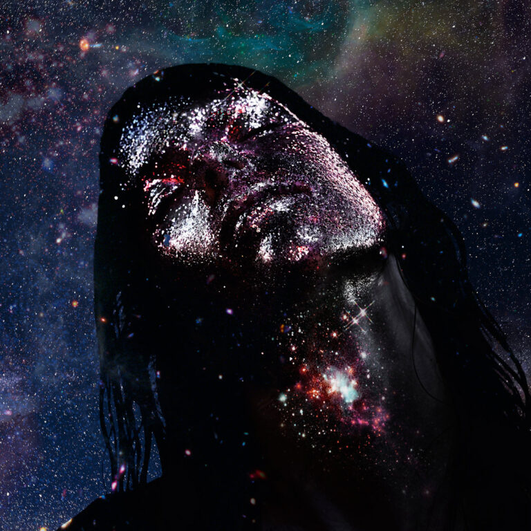 Ein in Sternennebel getauchtes Gesicht, dessen Haut wie von glitzernden Partikeln überzogen wirkt, kosmisch und entrückt in eine dunkle Galaxie eingebettet.