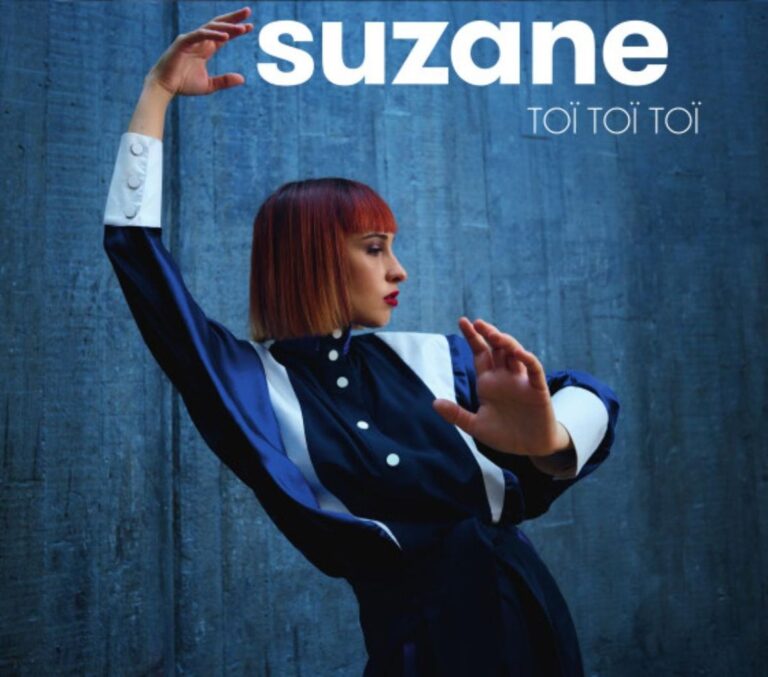 Suzane posiert auf dem Cover von Toï Toï in geometrischer Bewegung vor einer blauen Betonwand, in dunkelblauer Kombination mit weißen Akzenten – streng, zugleich elegant und voller Energie.