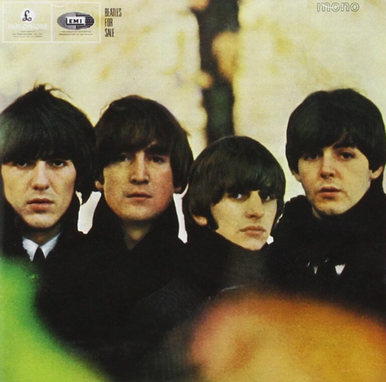 Vier junge Männer mit ernsten Gesichtern, eng aneinander, in dunklen Mänteln vor unscharfem Herbsthintergrund – das Cover von Beatles for Sale zeigt Nachdenklichkeit und Müdigkeit hinter dem Ruhm.