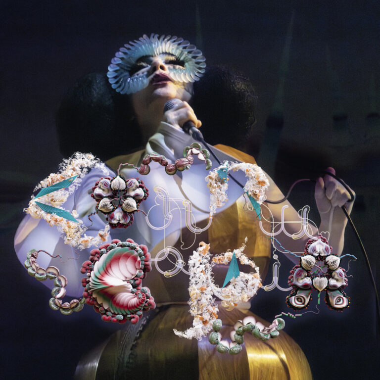 Die isländische Musikerin Björk in einer futuristischen Performance mit Maske und goldenem Kostüm, umgeben von organisch anmutenden Ornamenten, die Natur und Technologie verschmelzen lassen.