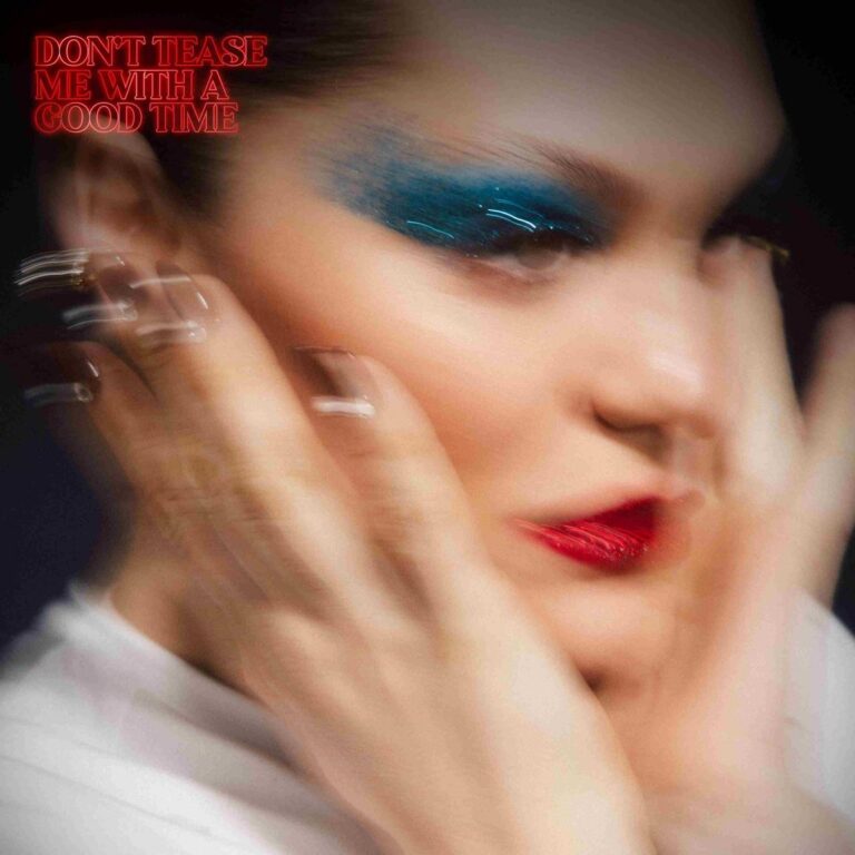 Verschwommenes Porträt mit bewegten Händen vor dem Gesicht, kräftigem blauem Lidschatten und roten Lippen, rotem Albumtitel links oben.