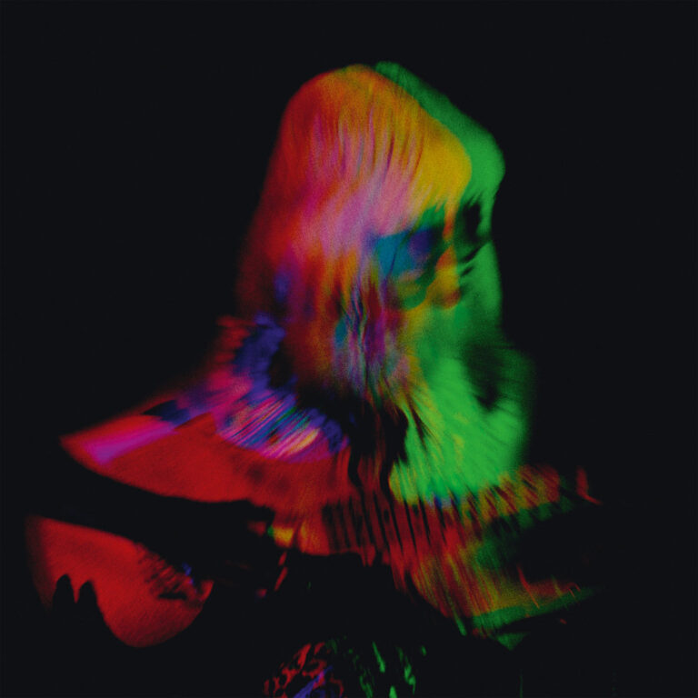 Mehrfach belichtete Figur mit Gitarre in leuchtenden Rot, Grün und Blau, die vor schwarzem Hintergrund verschwimmt und einen psychedelischen Effekt erzeugt.