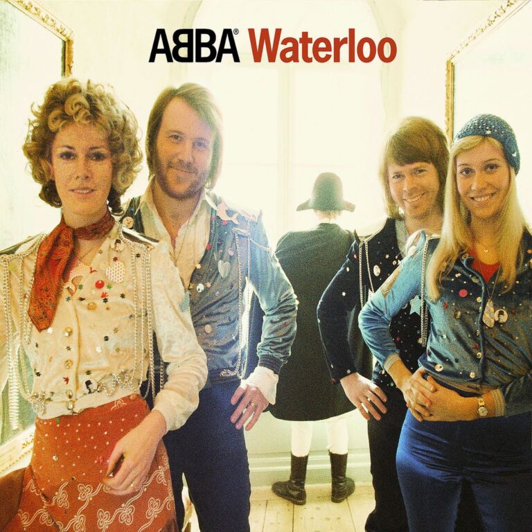 Helle Fotografie von ABBA in barock inspirierten Kostümen, frontal in einem lichtdurchfluteten Raum stehend; im Hintergrund eine Figur mit Napoleon-Hut, die dem Fenster den Rücken zukehrt.