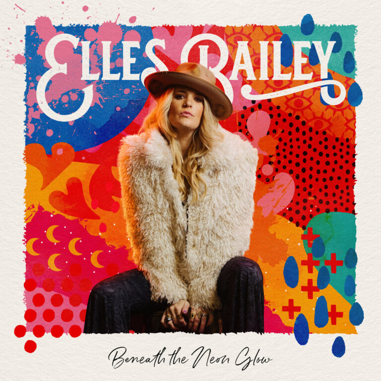 Elles Bailey sitzt frontal vor einem farbintensiven, grafisch gestalteten Hintergrund, selbstbewusst inszeniert zwischen Retro-Ästhetik und moderner Pop-Ikonografie.